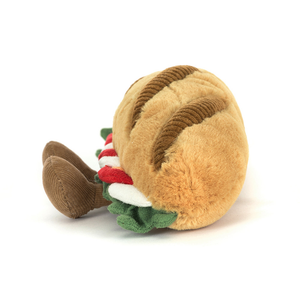Side view of a Jellycat plush toy shaped like a caprese baguette with brown feet on a white background.