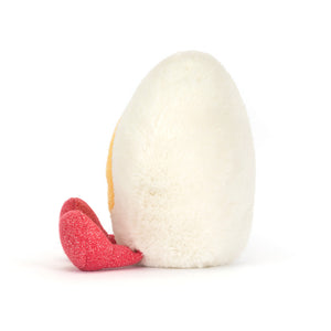 Side view of a Jellycat white egg heart-shaped plush toy with red sparkly feet on a white background