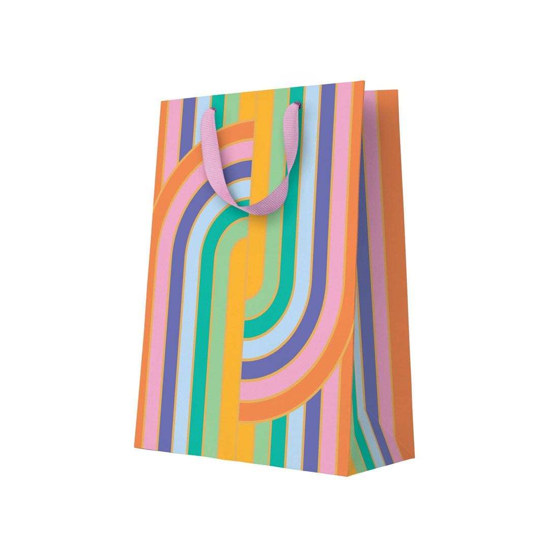 Colorful striped gift bag with pink handles on a white background.