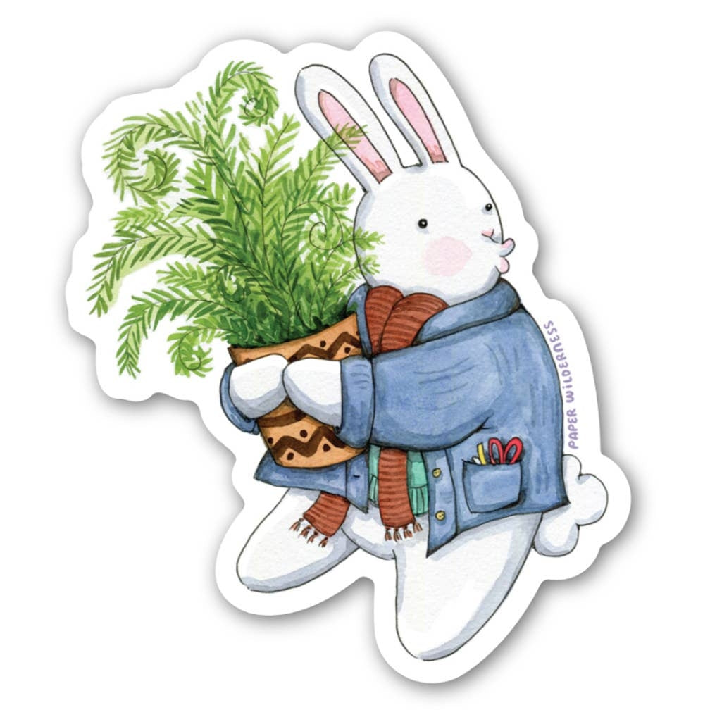 Sticker of a white rabbit wearing a blue sweater and scarf while holding a potted plant on a white background.