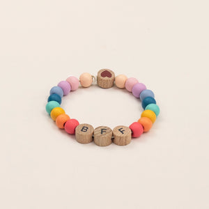 Bracelet with colourful beads and  wooden beads spelling 'BFF' on a white background.