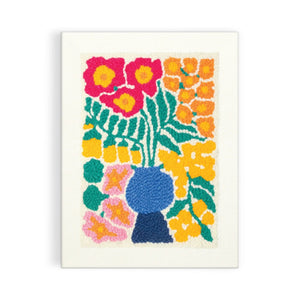 Finished punch needle design of a plant in a blue vase surrounded by colourful flowers. 
