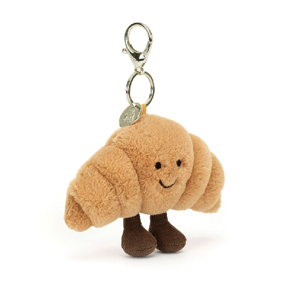 adorably soft bag charm of a smiling croissant with legs by popular brand Jellycat.