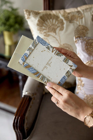 Person holding a photo frame cotton card with a blue, green and gold botanical design in a home setting. The text 'Happy Birthday To You' is printed on the card. 