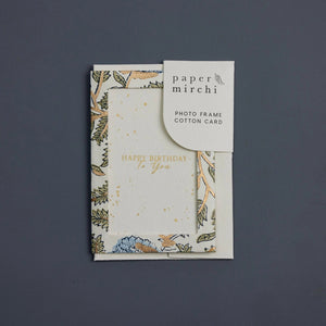 Photo frame cotton card with a blue, green and gold botanical design and 'Happy Birthday To You' text. The card sits on a blue background. 