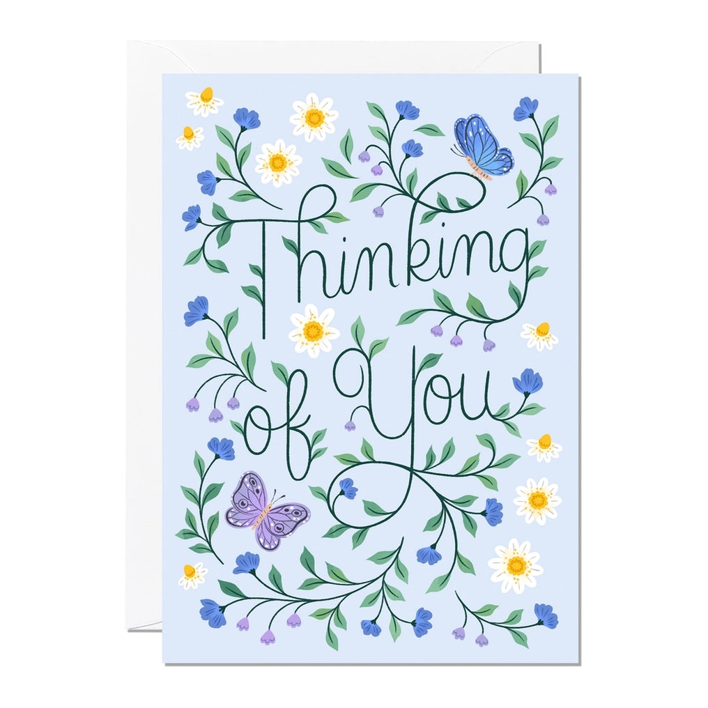 Greeting card with a floral and butterfly design on a blue background with the text 'Thinking Of You'.