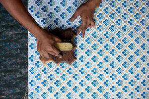 Person using a wooden tool to print a botanical design on a white surface.