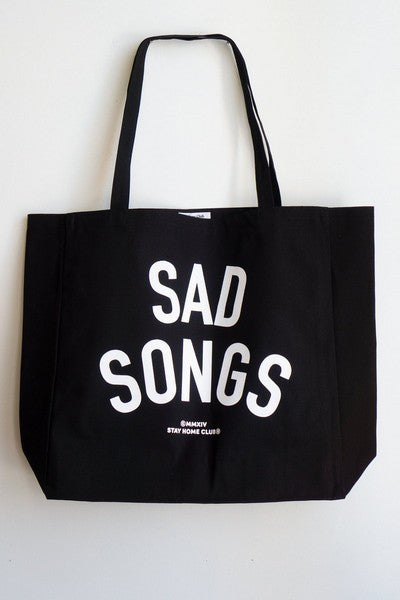 large black tote bag with white text that reads "sad songs"